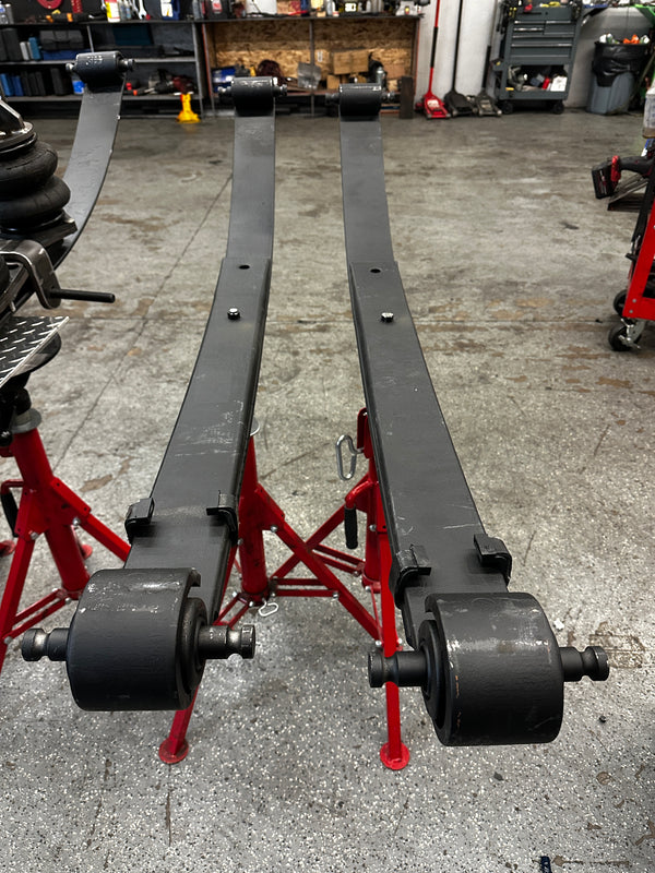 Heavy duty truck leaf springs on red stands in an auto repair shop