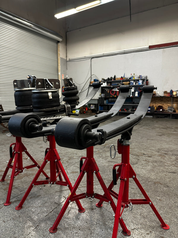 Heavy duty truck leaf springs and air suspension parts on red stands in repair shop