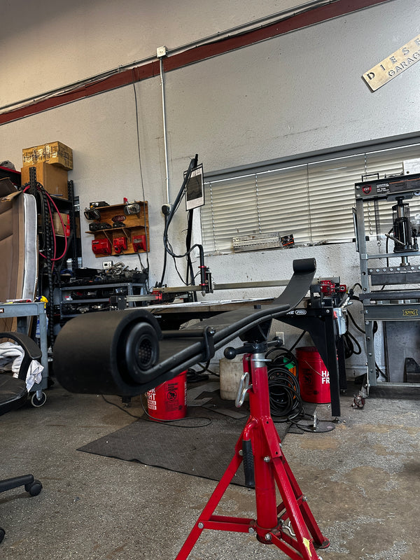 Heavy duty truck leaf spring mounted on red jack stand in auto repair shop