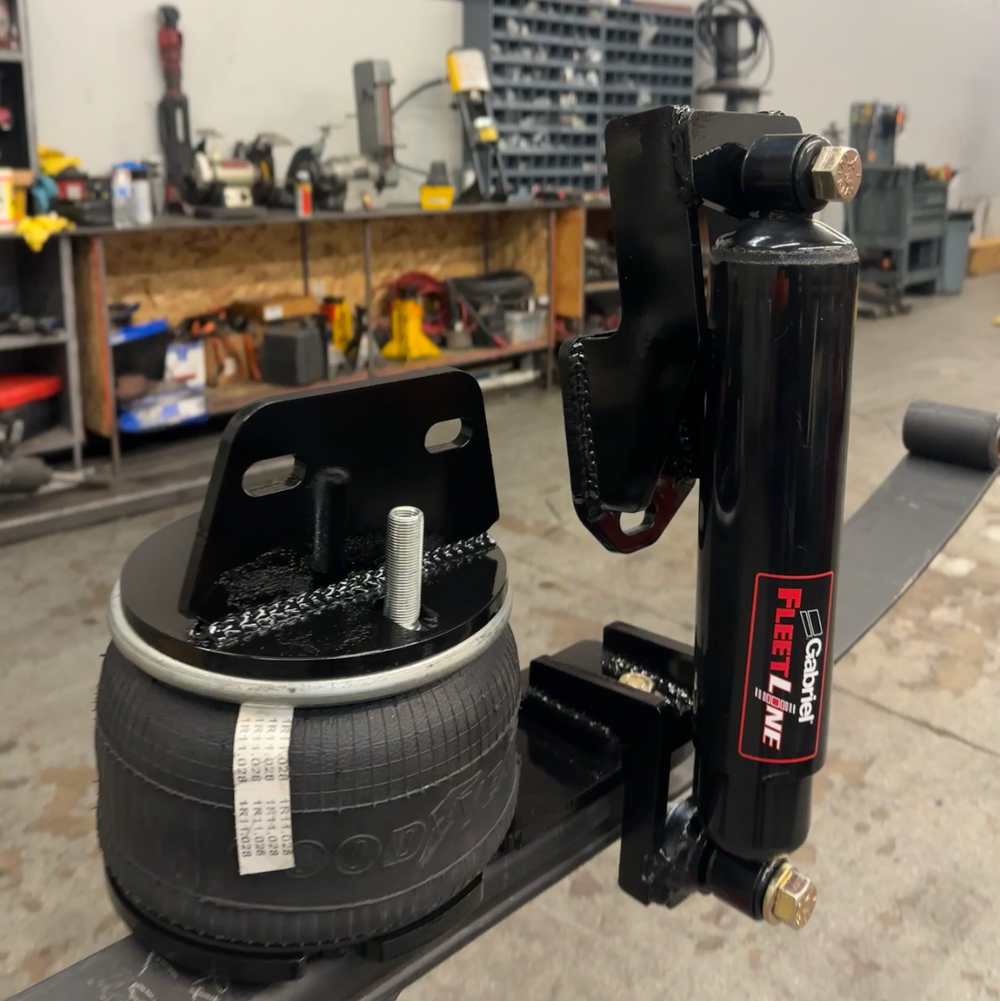Tire and jack set on a stand in a workshop with 'Built by Wolf' sign in the background.