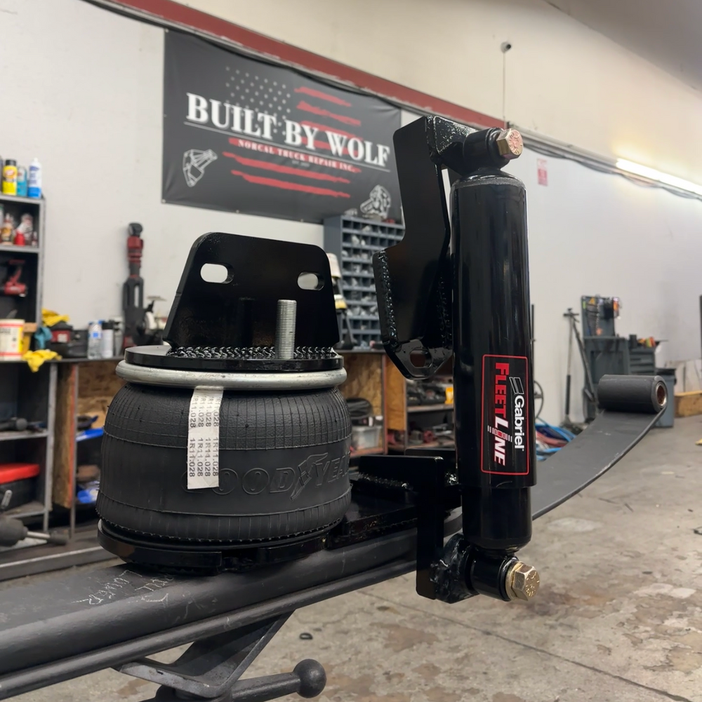 Tire on a lift in a garage with 'Built by Wolf' sign in the background