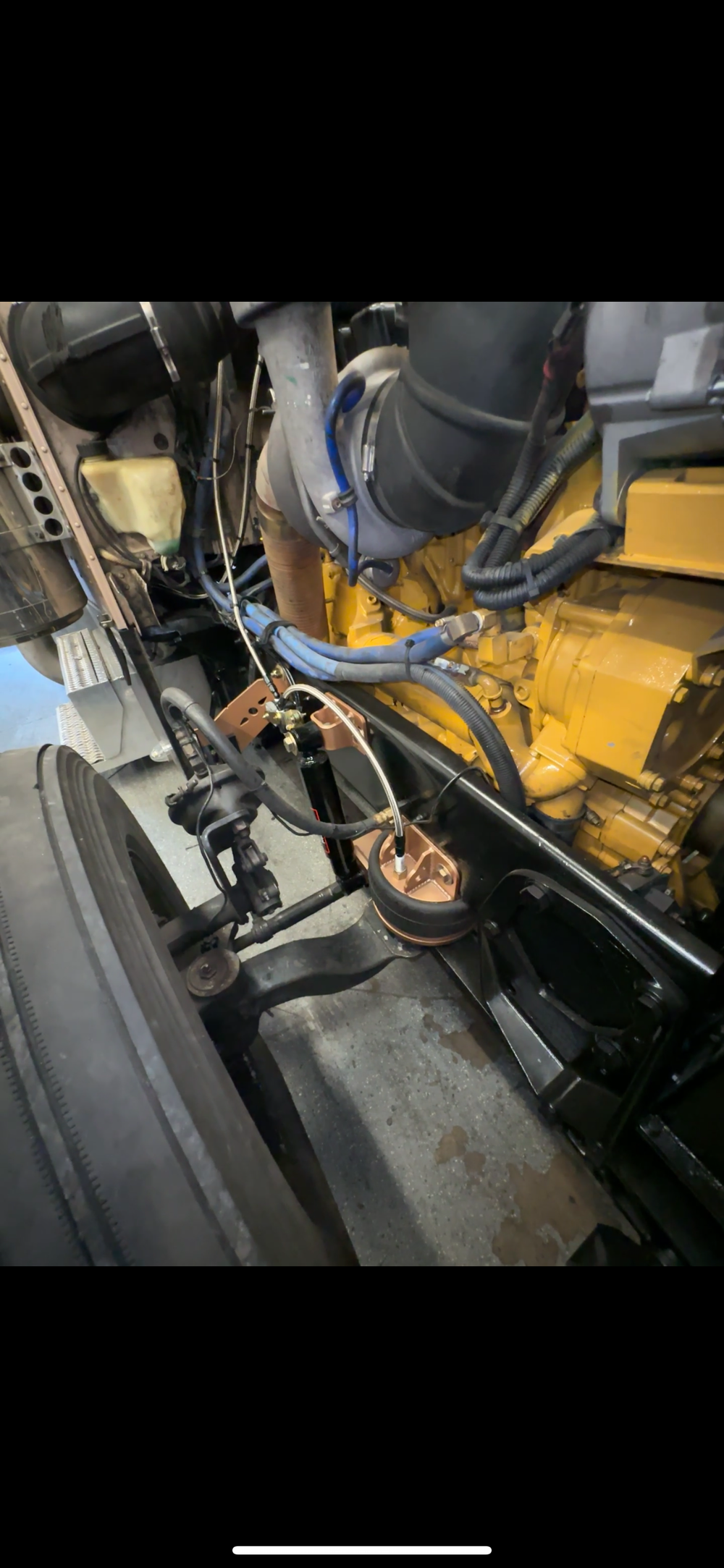 Heavy duty truck engine and suspension components with visible hoses and wiring.