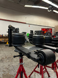 Heavy duty truck suspension components and air springs on red stands in a repair shop