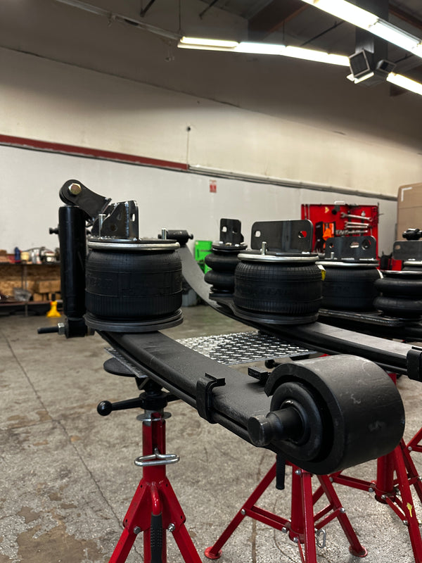 Heavy duty truck suspension components and air springs on red stands in a repair shop