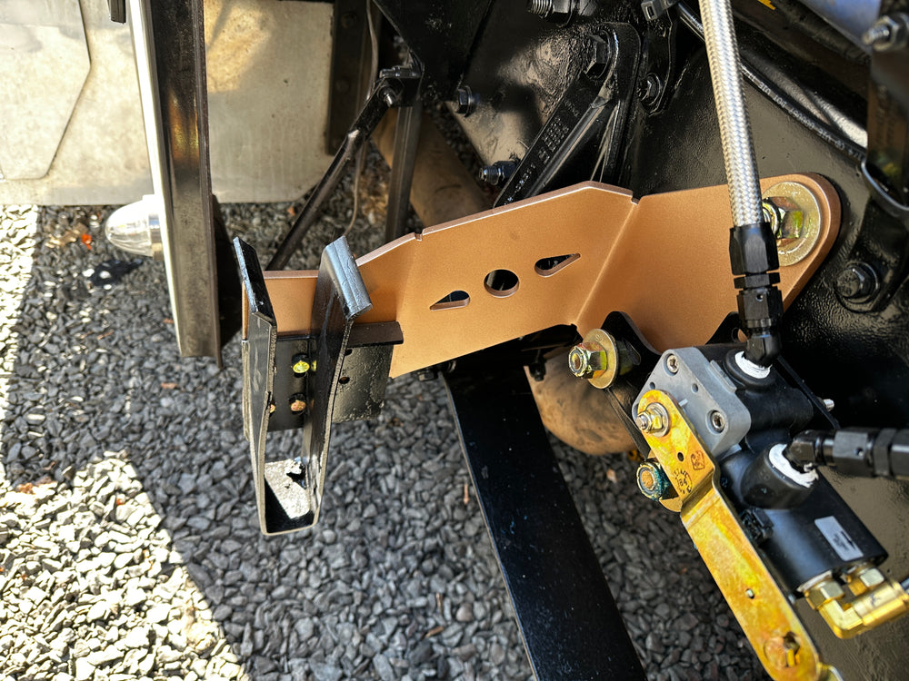 Heavy duty truck suspension bracket and hydraulic lines on gravel surface