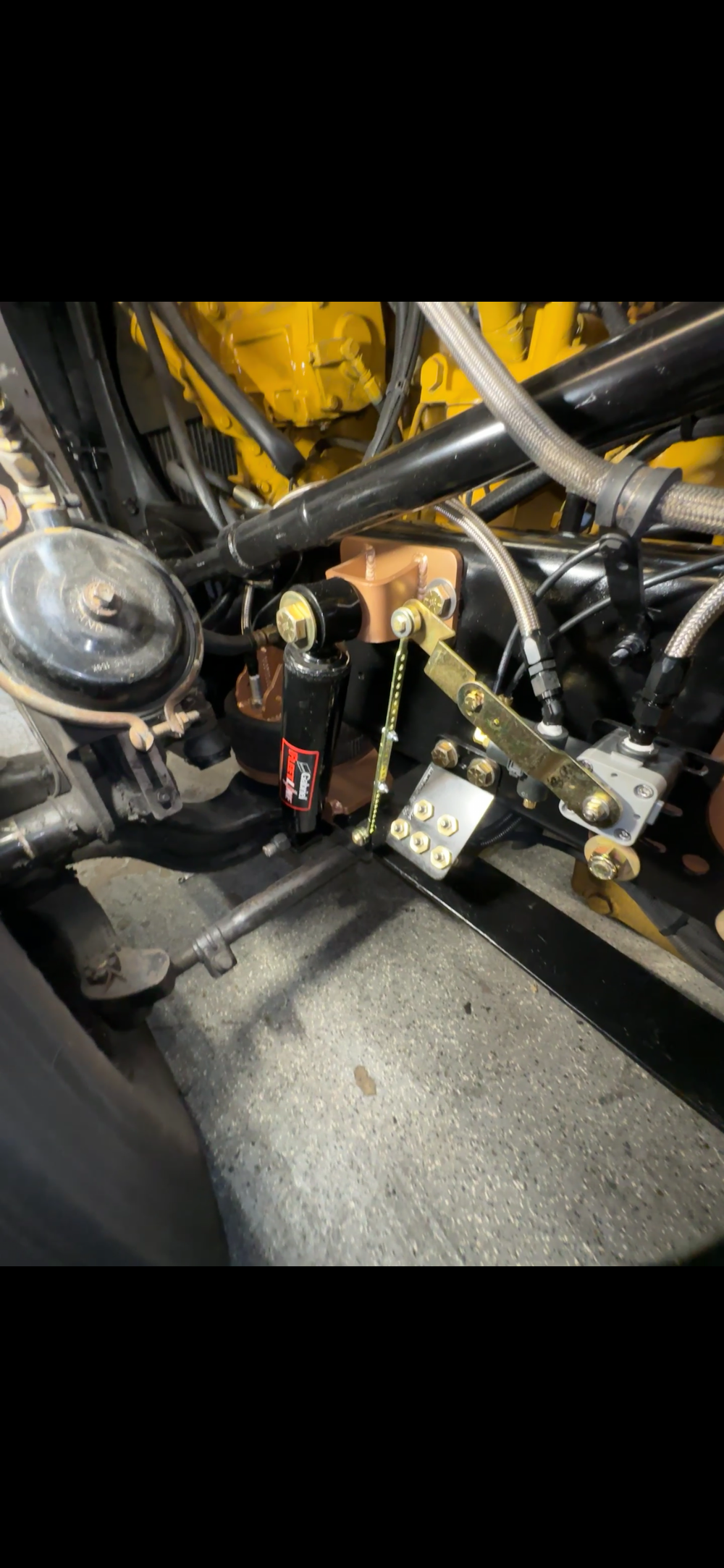 Heavy duty truck steering linkage, hydraulic lines, and engine components close-up