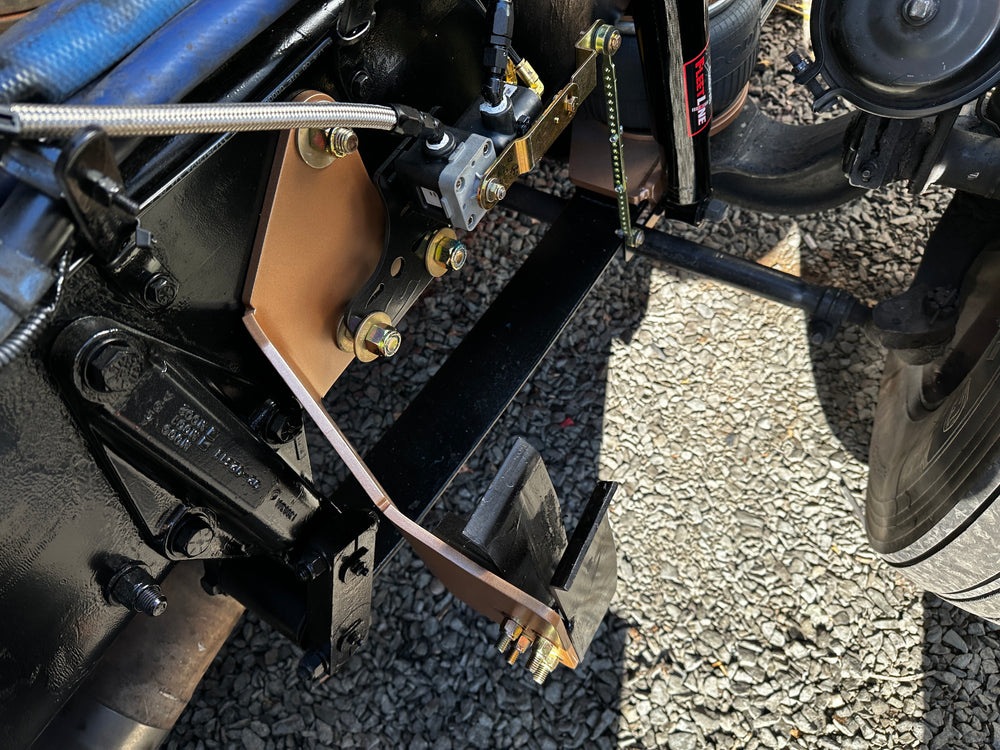 Heavy duty truck suspension and custom bracket assembly with metal bolts on gravel