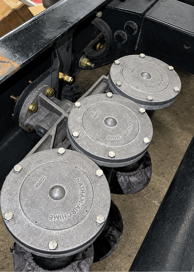 Three gray cast iron winch pulleys with visible 'NANAMARCHE' branding, attached to a black metal frame in an industrial setting.