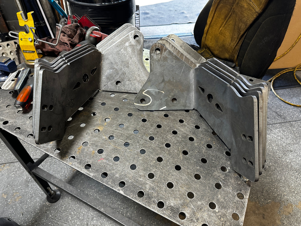 Heavy duty steel truck bracket plates stacked on a metal workbench in a repair shop