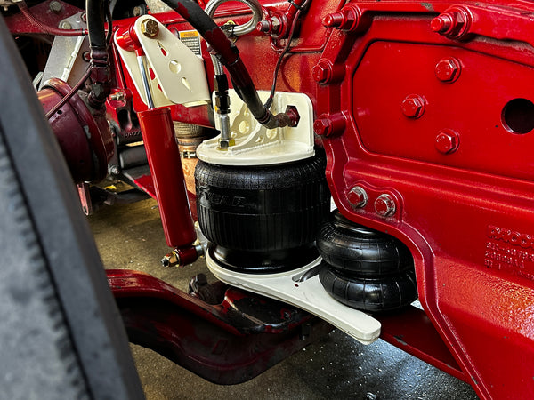 Heavy duty truck suspension with air springs, shocks, and red-painted chassis closeup