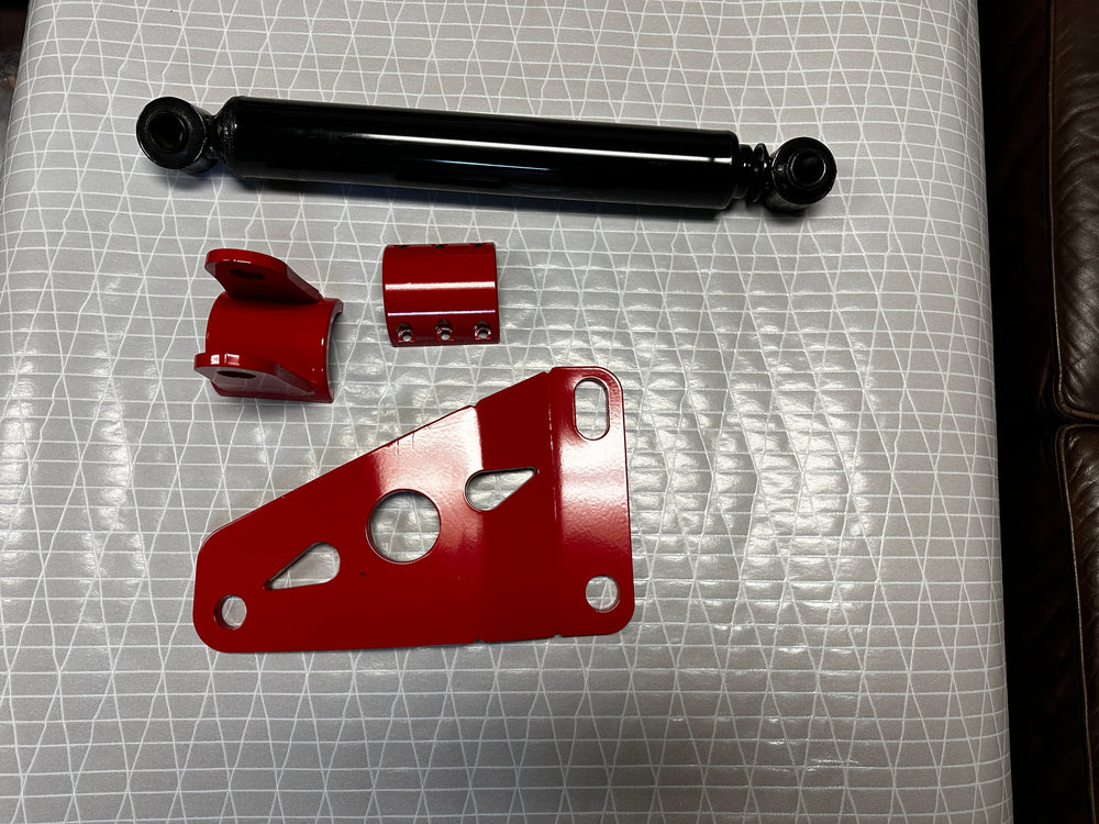 Heavy duty truck suspension components including black shock absorber and red brackets on table