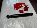 Heavy duty truck suspension parts, black shock absorber and red metal brackets on a table.