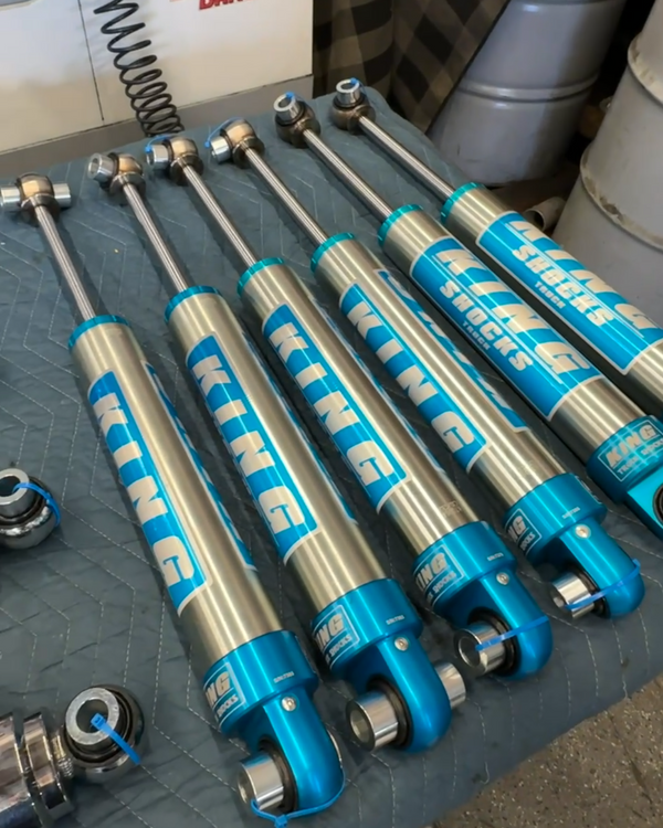 Set of shock absorbers on a workshop table with visible branding.