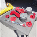 A set of red and silver air suspension components, including a K&N brand shock absorber and air cylinders, displayed on a gray textured mat on a workbench in a garage.