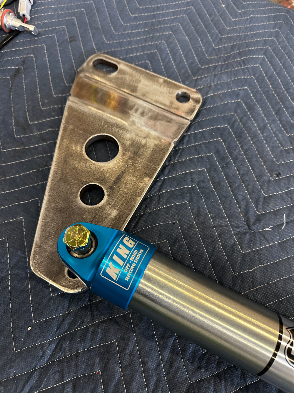 Off-road racing shock absorber and custom metal truck bracket on quilted surface