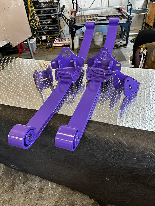 Pair of purple heavy duty truck suspension leaf springs and brackets on a metal workbench