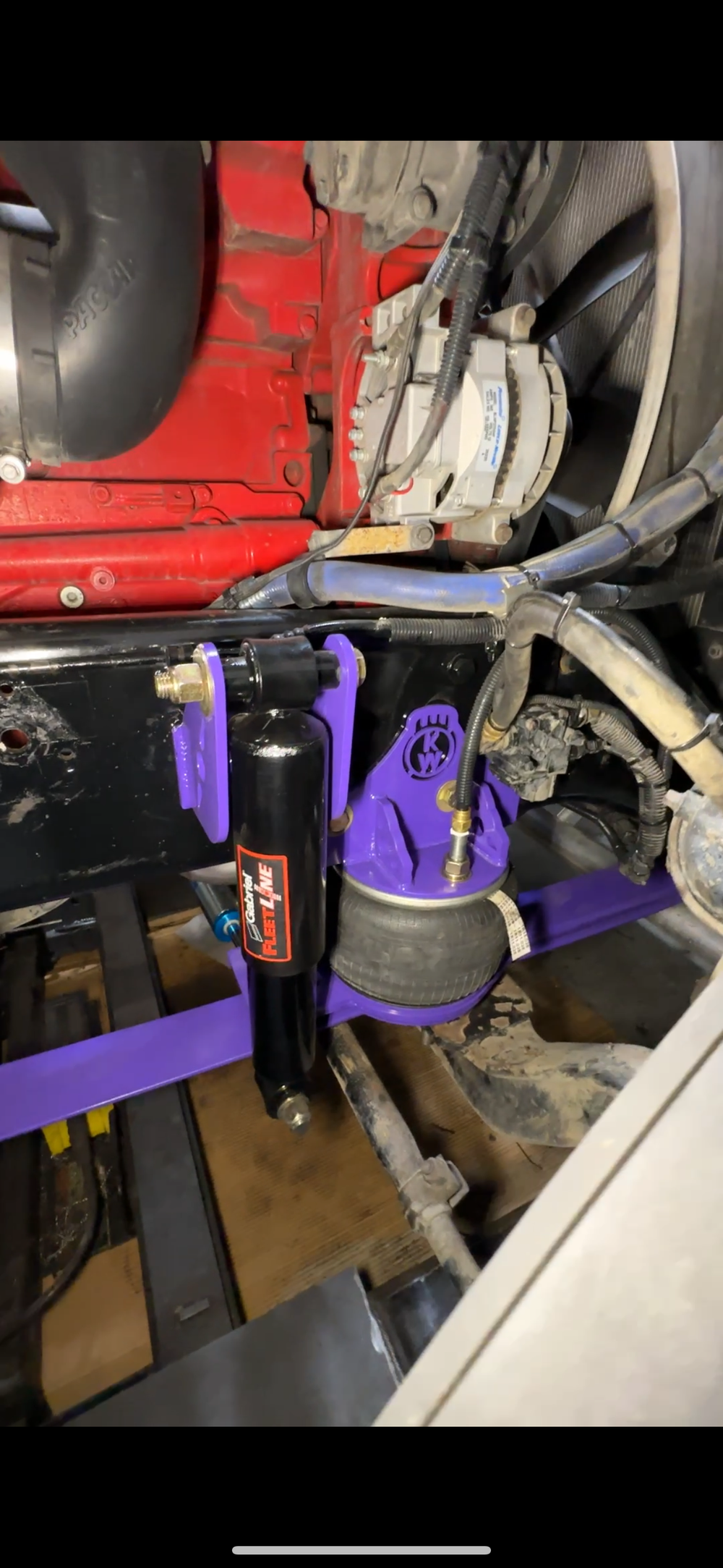 Heavy duty truck air suspension with purple shock mount and airbag under engine bay