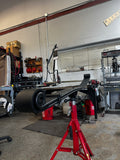Heavy duty truck leaf spring mounted on red jack stand in auto repair shop