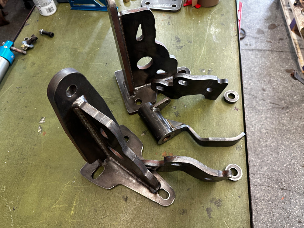 Custom fabricated heavy duty steel brackets for truck repair on a workshop table