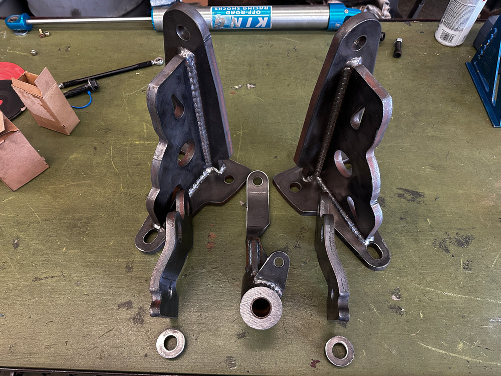 Heavy duty custom fabricated metal brackets and linkage components on workbench