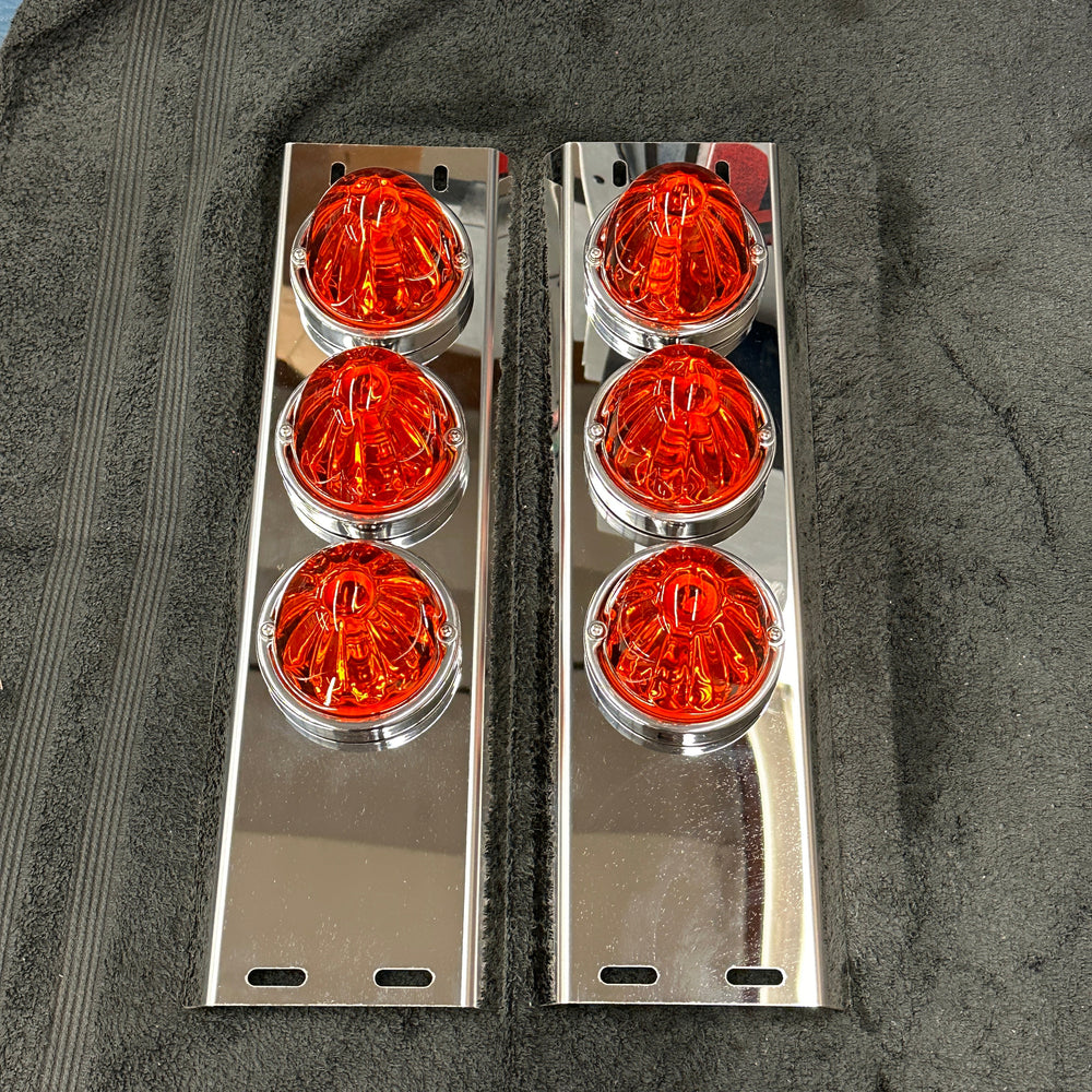 Two sets of orange circular lights with chrome frames on a dark surface.