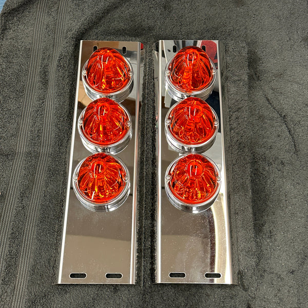 Two sets of orange circular lights with chrome frames on a dark surface.