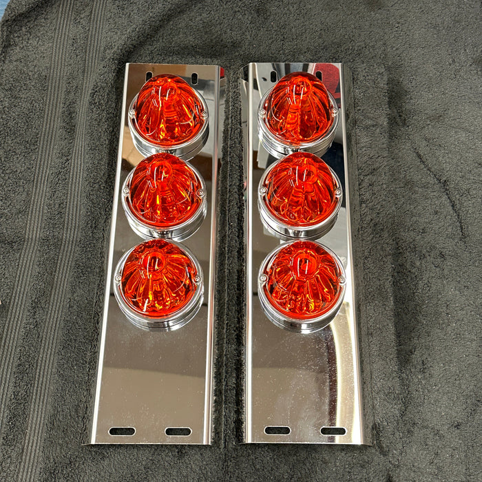 Two sets of orange circular lights with chrome frames on a dark surface.